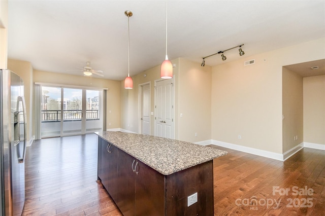 kitchen with dark wood-type flooring, dark brown cabinetry, stainless steel fridge, pendant lighting, and ceiling fan