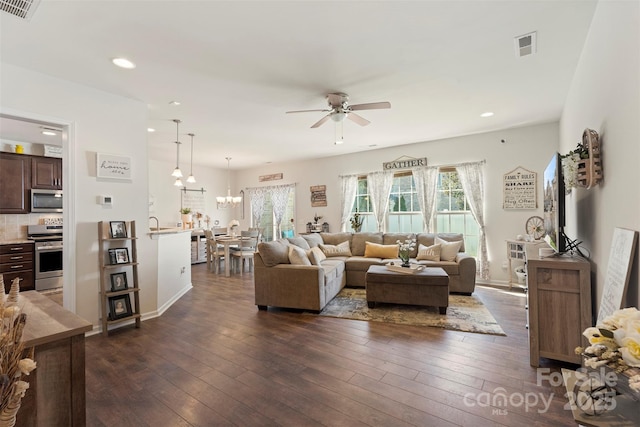 living area featuring visible vents, dark wood-style floors, and ceiling fan with notable chandelier