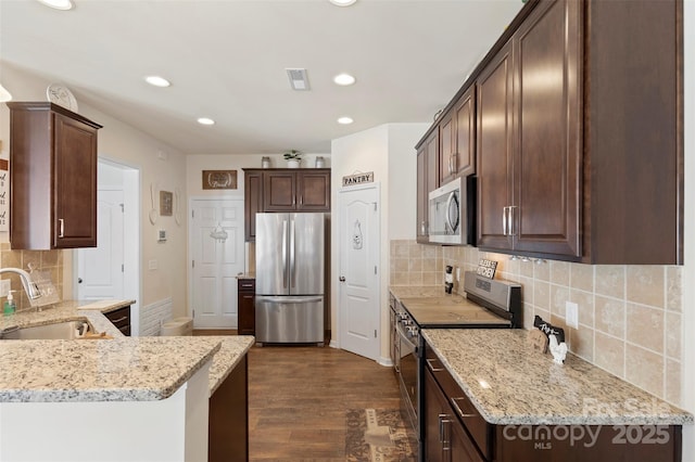 kitchen with visible vents, dark wood-type flooring, a sink, dark brown cabinetry, and appliances with stainless steel finishes