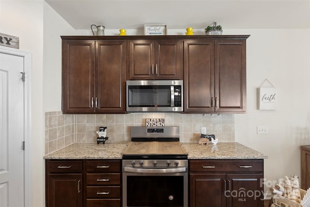 kitchen featuring decorative backsplash, dark brown cabinetry, light stone countertops, and appliances with stainless steel finishes