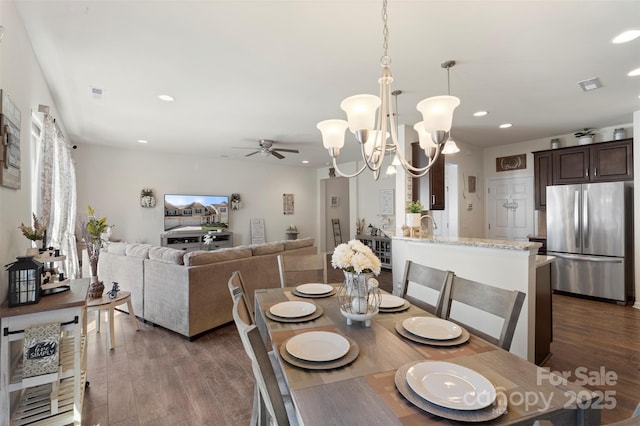 dining space with visible vents, recessed lighting, ceiling fan with notable chandelier, and dark wood-style flooring