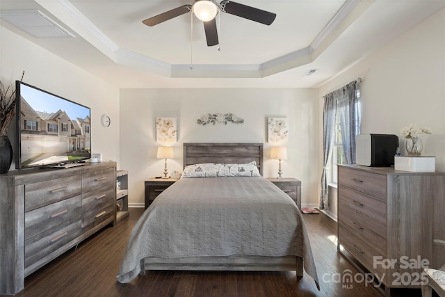 bedroom with a raised ceiling, crown molding, dark wood-style floors, and visible vents