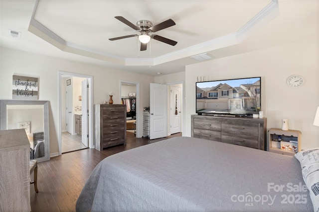 bedroom featuring a tray ceiling, visible vents, dark wood-style flooring, and crown molding