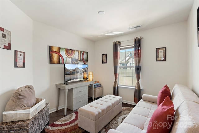 living room featuring visible vents, baseboards, and wood finished floors