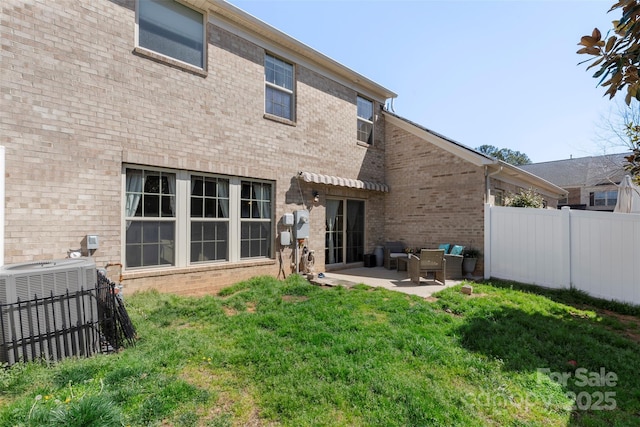 rear view of house with a patio, cooling unit, fence, a yard, and brick siding