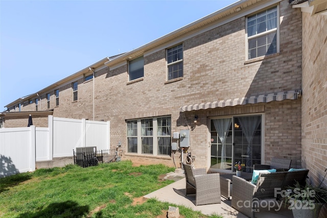 rear view of property with a patio area, a yard, fence, and brick siding