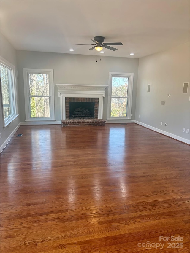 unfurnished living room featuring plenty of natural light, dark wood-style flooring, and a fireplace