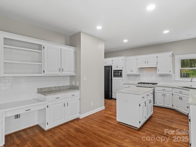 kitchen featuring a center island, open shelves, stainless steel microwave, white cabinets, and wood finished floors