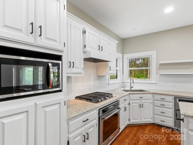 kitchen with decorative backsplash, white cabinetry, stainless steel appliances, and a sink