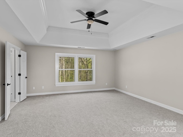 unfurnished bedroom with light colored carpet, visible vents, a raised ceiling, and ornamental molding