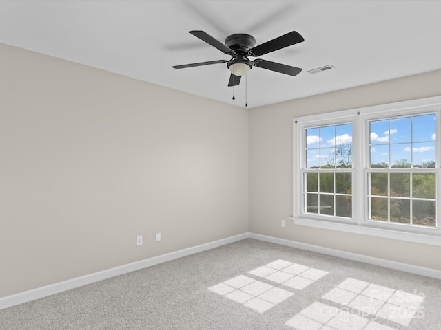 empty room featuring visible vents, ceiling fan, light colored carpet, and baseboards