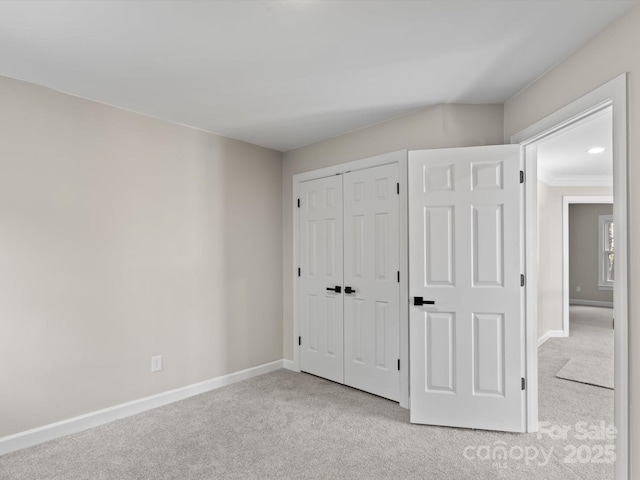 unfurnished bedroom featuring a closet, light carpet, and baseboards