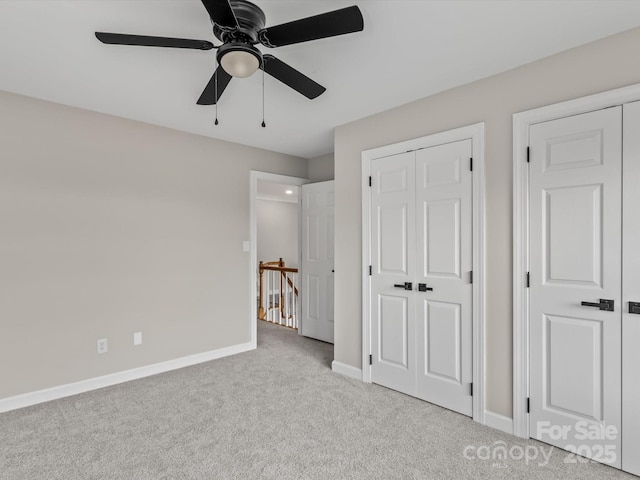 unfurnished bedroom with light carpet, a closet, a ceiling fan, and baseboards