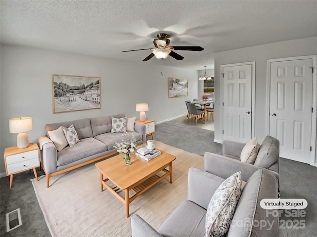 living room with ceiling fan, carpet flooring, and a textured ceiling