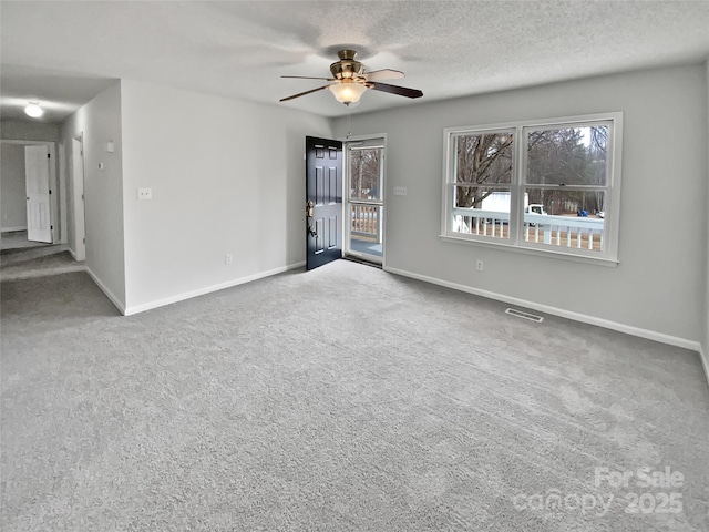 carpeted spare room featuring ceiling fan and a textured ceiling