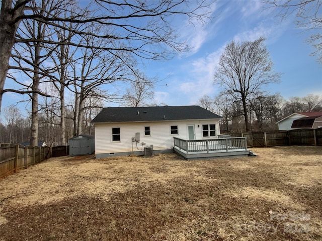 rear view of property with a storage unit, a deck, a lawn, and central air condition unit