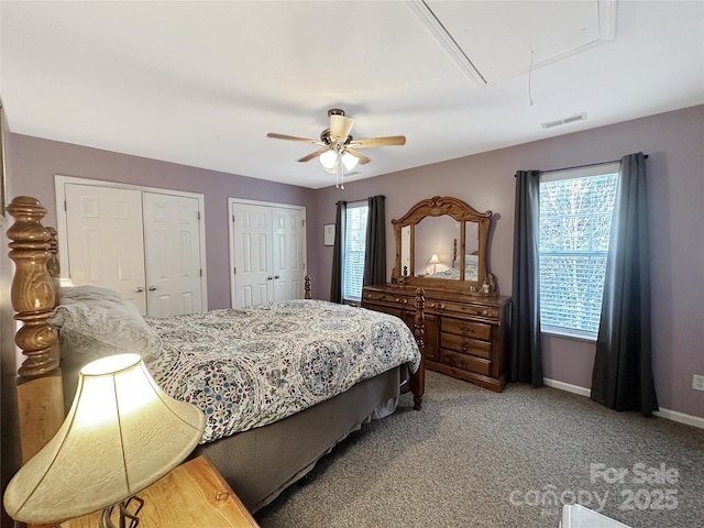 bedroom with two closets, ceiling fan, and carpet flooring