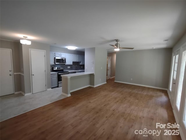 kitchen featuring tasteful backsplash, sink, hardwood / wood-style flooring, kitchen peninsula, and stainless steel appliances