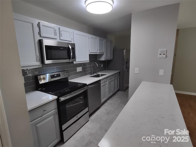 kitchen with tasteful backsplash, appliances with stainless steel finishes, sink, and white cabinets