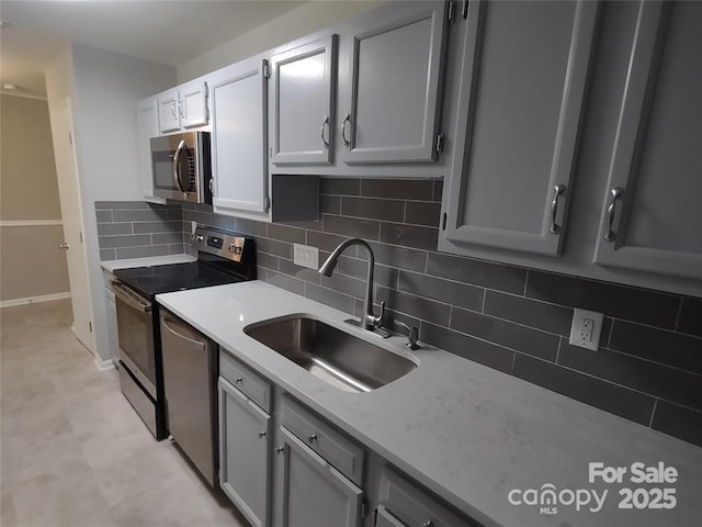 kitchen with tasteful backsplash, sink, gray cabinets, and stainless steel appliances