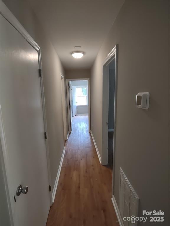 corridor with hardwood / wood-style flooring