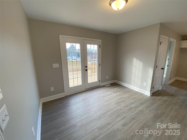 entryway with french doors, wood finished floors, and baseboards