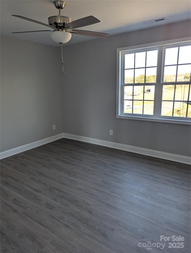 empty room featuring dark wood-style floors, baseboards, visible vents, and a ceiling fan