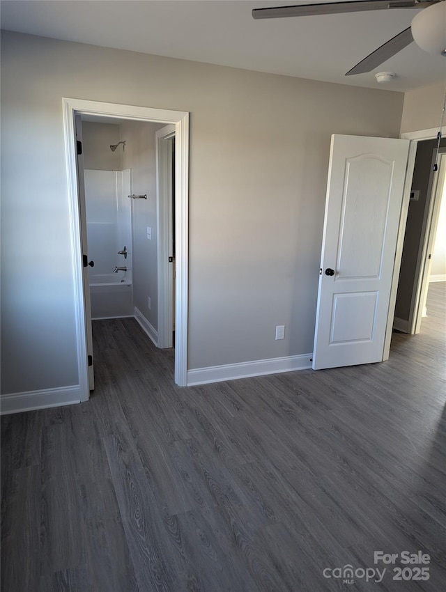 empty room with dark wood finished floors, ceiling fan, and baseboards