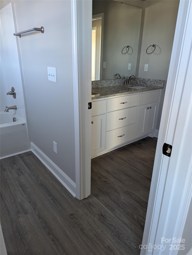 bathroom featuring double vanity, a sink, baseboards, and wood finished floors