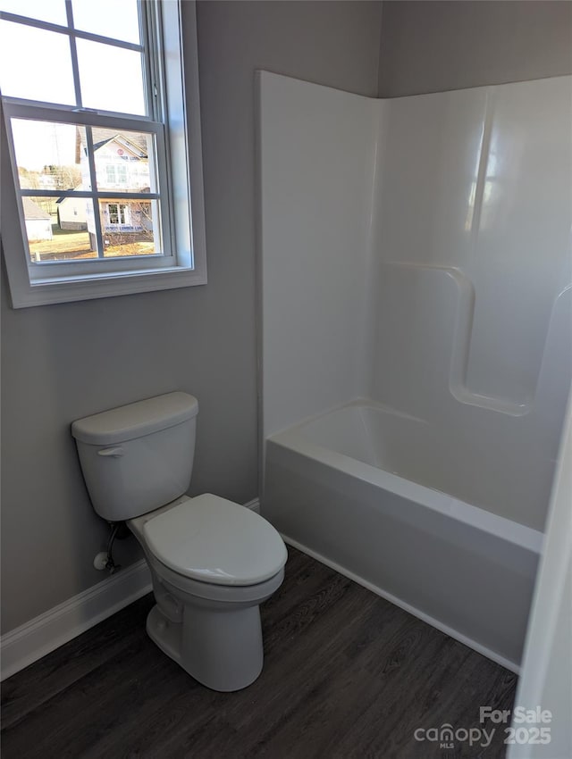 full bathroom featuring shower / washtub combination, baseboards, toilet, and wood finished floors