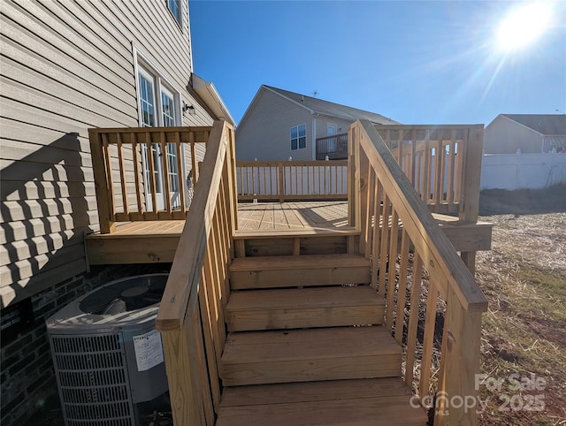 wooden deck with central air condition unit, fence, and stairway