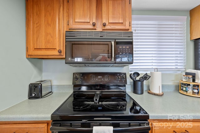 kitchen featuring black appliances, light countertops, and brown cabinets