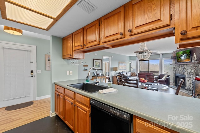 kitchen featuring visible vents, dishwasher, open floor plan, light countertops, and a sink