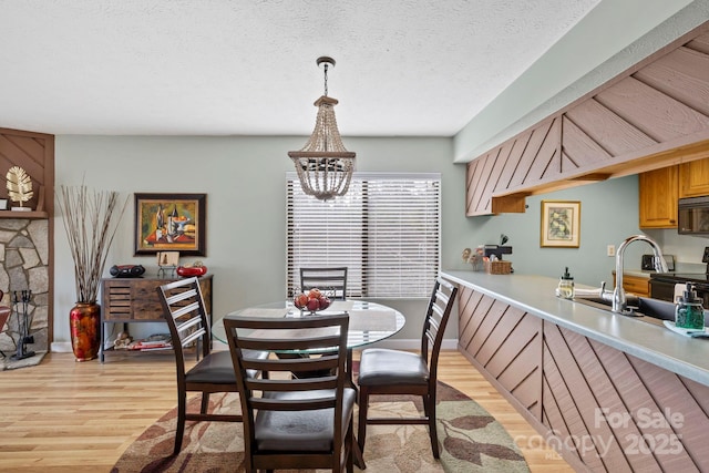 dining room with light wood-type flooring, a chandelier, and a textured ceiling