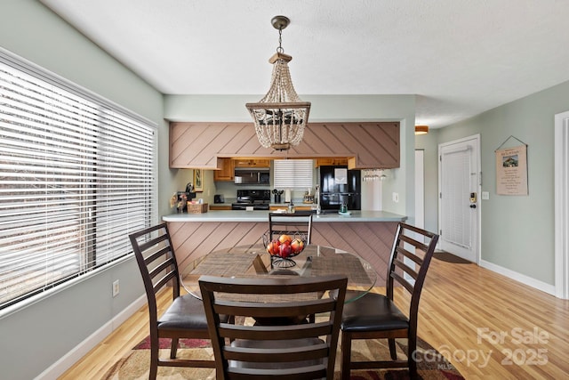 dining area featuring a chandelier, baseboards, and light wood finished floors