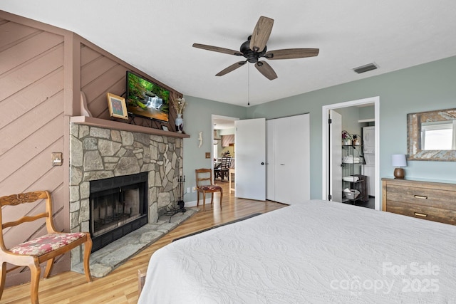 bedroom with light wood-style flooring, a fireplace, visible vents, and a ceiling fan