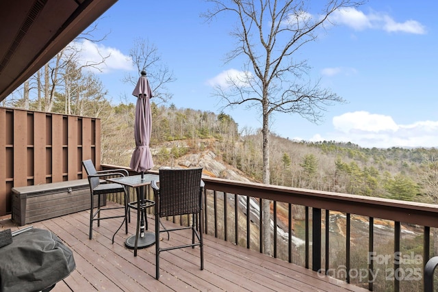 wooden terrace featuring a view of trees