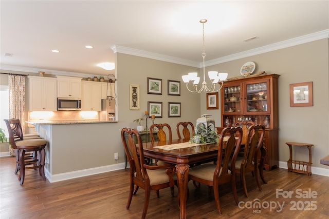 dining room featuring an inviting chandelier, ornamental molding, and dark hardwood / wood-style floors