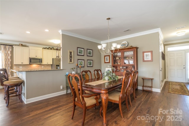 dining room with dark wood-type flooring, ornamental molding, and a chandelier