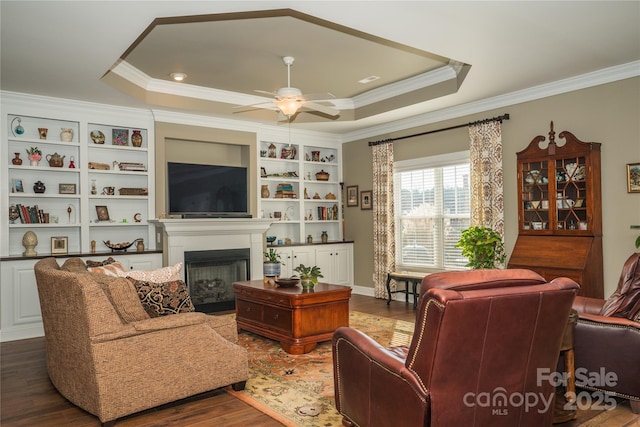 living room with ornamental molding, dark hardwood / wood-style floors, and a tray ceiling