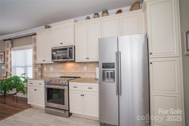 kitchen featuring stainless steel appliances, light stone countertops, backsplash, and light hardwood / wood-style flooring