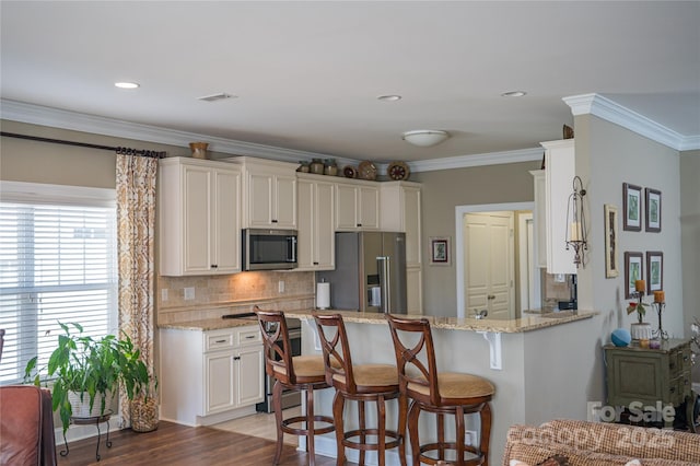 kitchen with light stone counters, appliances with stainless steel finishes, kitchen peninsula, and decorative backsplash