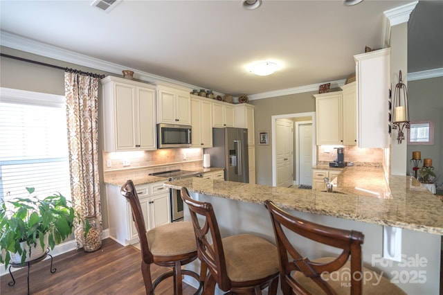 kitchen with light stone counters, appliances with stainless steel finishes, dark hardwood / wood-style flooring, kitchen peninsula, and decorative backsplash