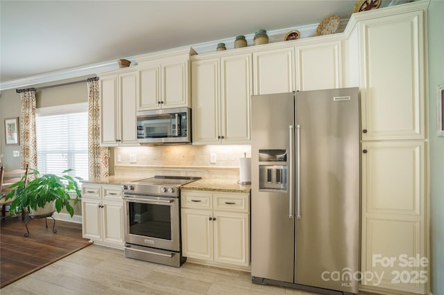 kitchen featuring appliances with stainless steel finishes, light stone countertops, decorative backsplash, and light wood-type flooring