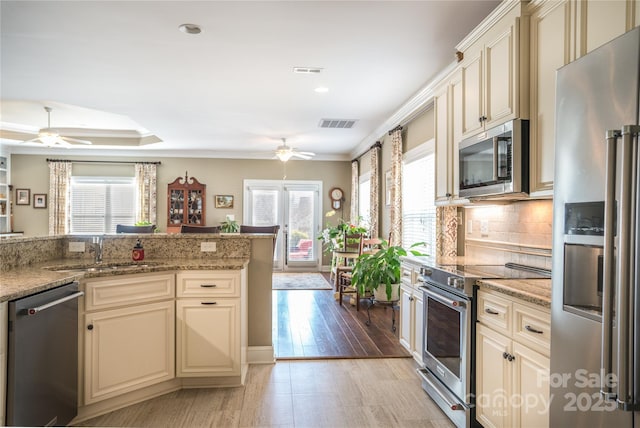 kitchen featuring a wealth of natural light, stainless steel appliances, and cream cabinetry