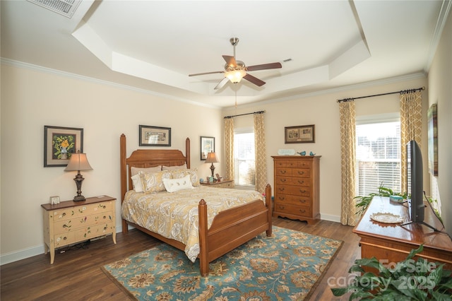 bedroom with multiple windows, dark wood-type flooring, ceiling fan, and a tray ceiling