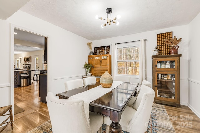 dining area featuring an inviting chandelier, a textured ceiling, and light hardwood / wood-style floors