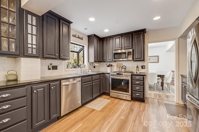 kitchen with sink, light hardwood / wood-style flooring, dark brown cabinets, stainless steel appliances, and tasteful backsplash