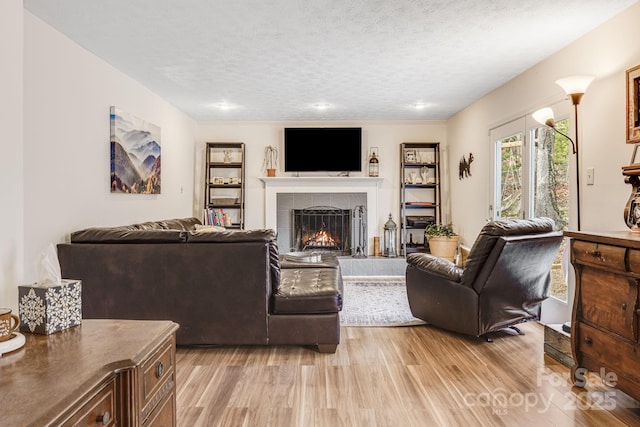 living room with a textured ceiling, a fireplace, and light wood-type flooring