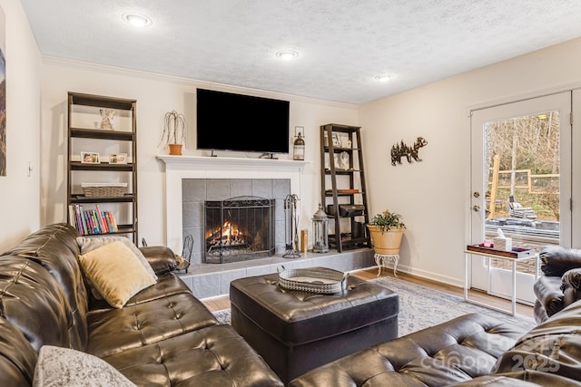 living room with a tile fireplace, ornamental molding, hardwood / wood-style floors, and a textured ceiling